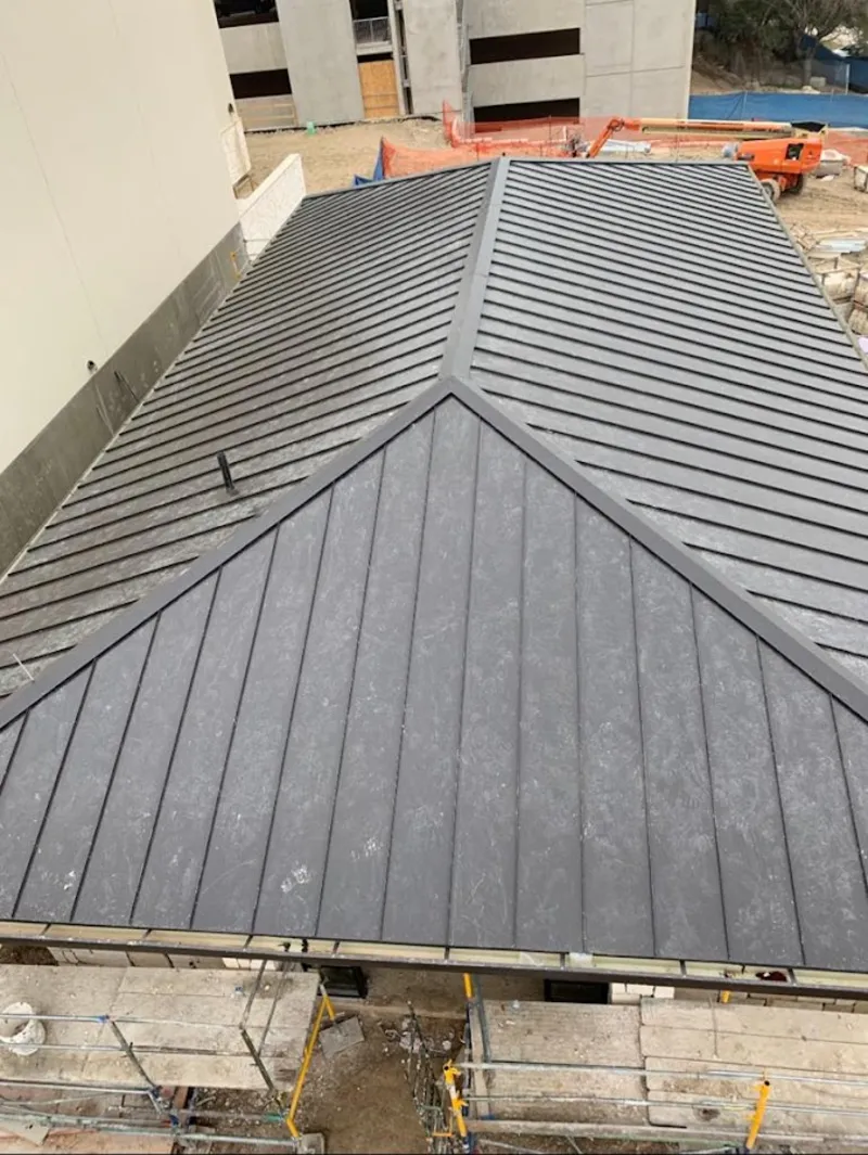 Commercial metal roof construction with crane equipment in Louisburg